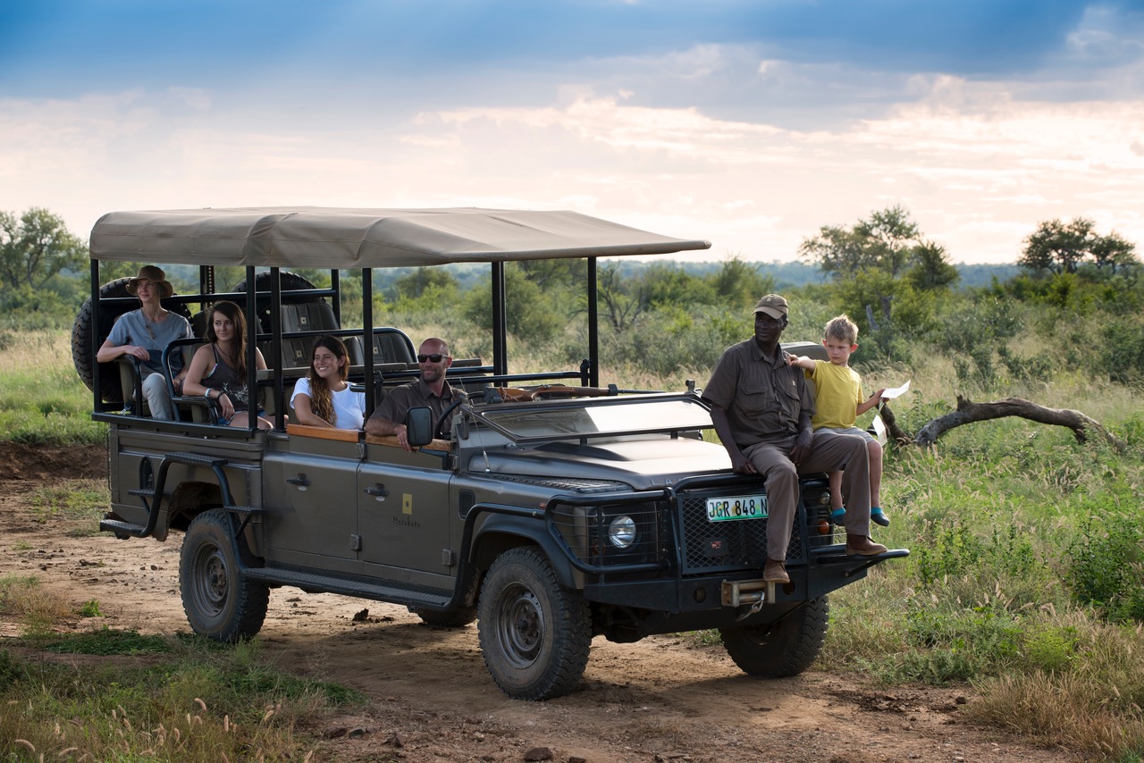Open game-drive vehicle with guests at golden hour